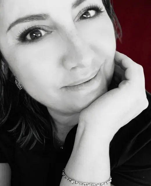 Retrato en blanco y negro de la autora, sonriendo con la mano apoyada en la mejilla