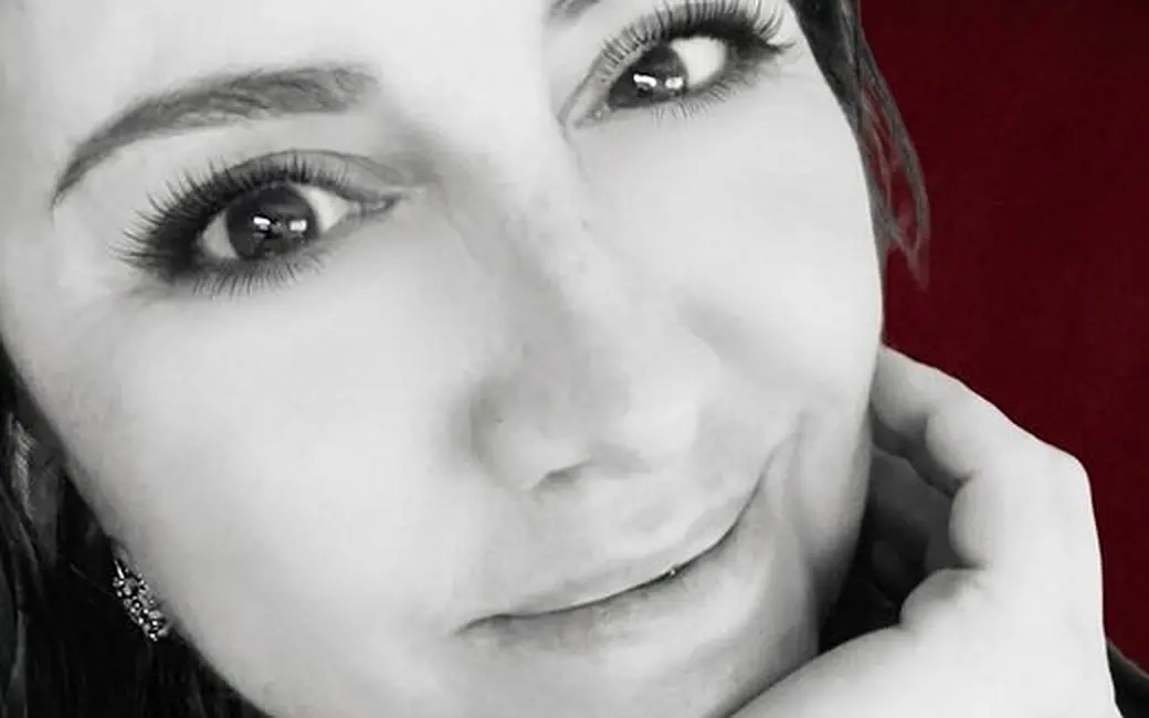 Retrato en blanco y negro de la autora, sonriendo con la mano apoyada en la mejilla